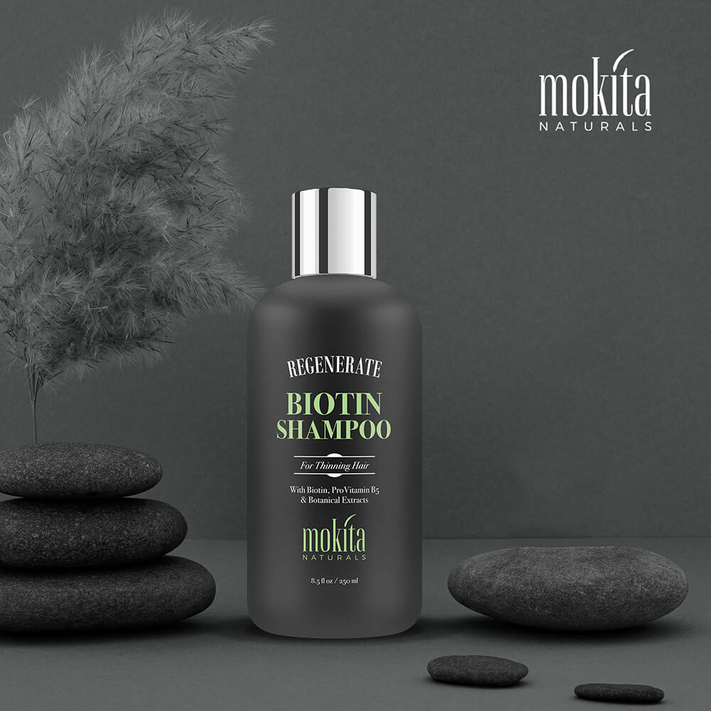 Black serum bottle labeled 'Regenerate Serum' by mokita on a green background with stones and a plant.