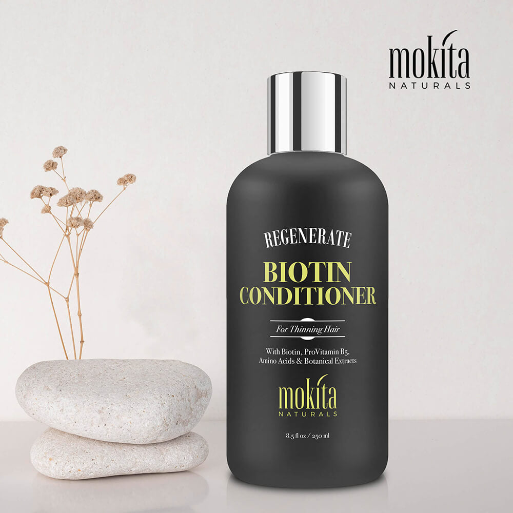 Biotin conditioner bottle with decorative stones and flowers on a light background