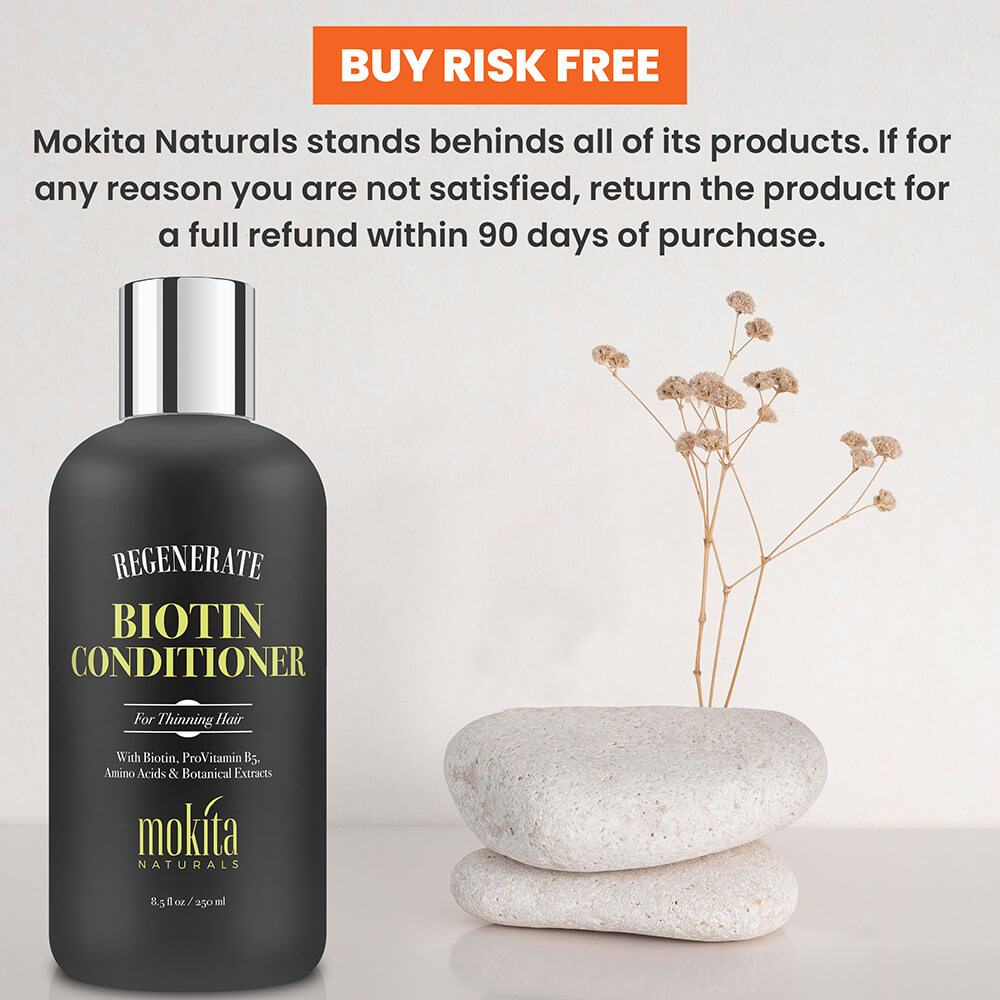 Mokita Naturals Biotin Conditioner bottle with decorative stones and plant on a light background
